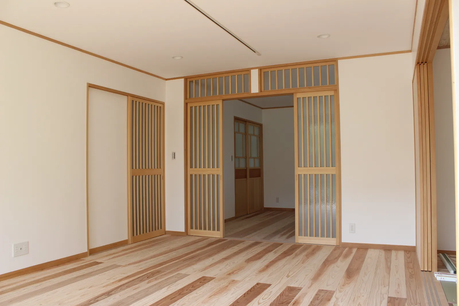 杉の床のリビングルームと、木製の格子引き戸