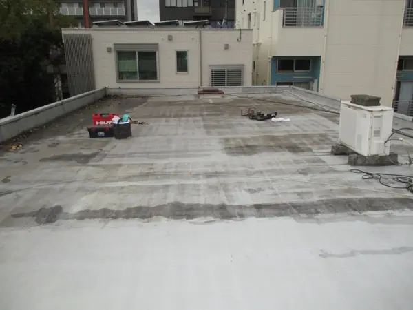 施工前の屋上を建物側に向かって見たところ。防水層が傷み、表面が黒ずんでいる