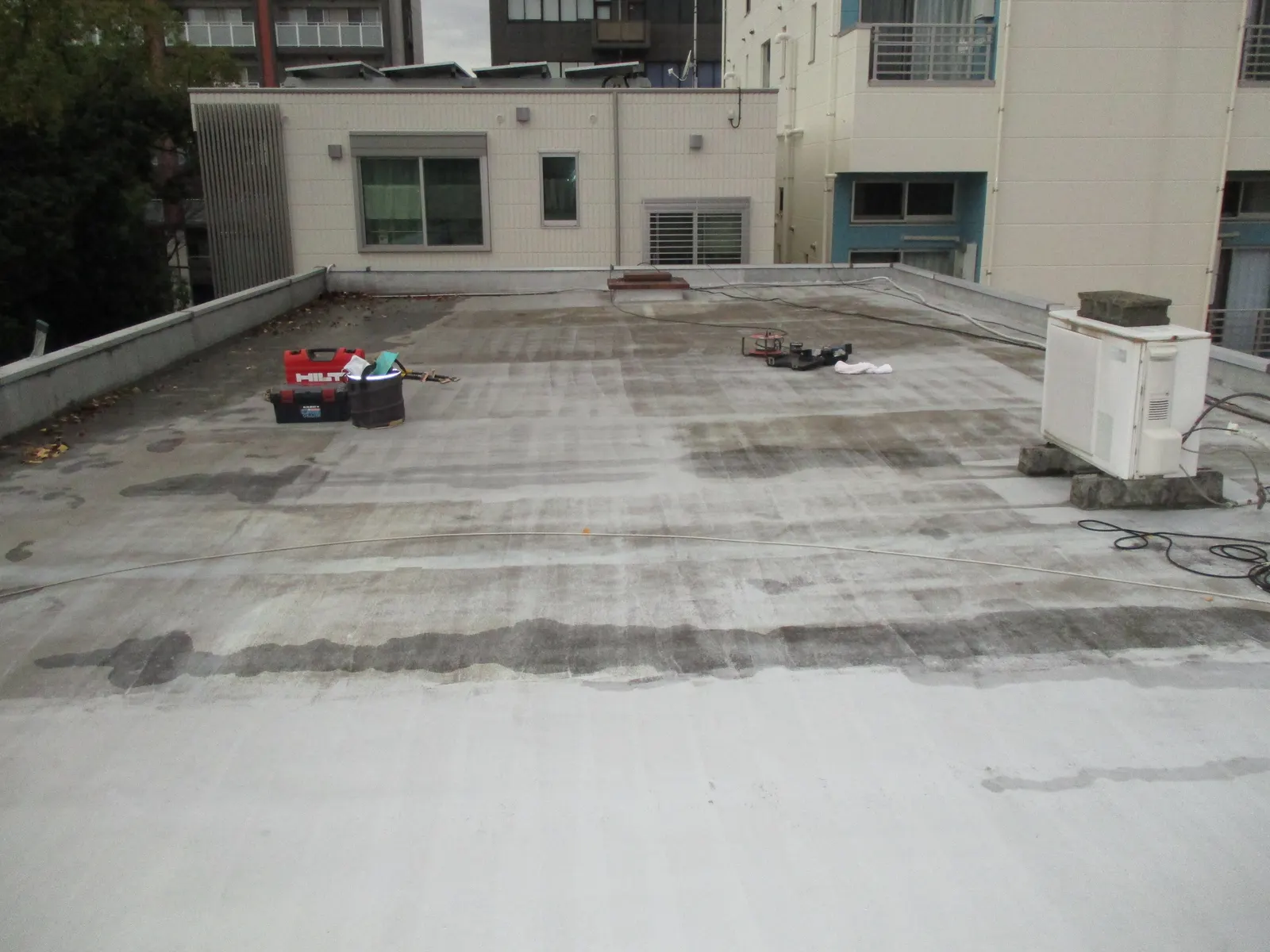 施工前の屋上を建物側に向かって見たところ。防水層が傷み、表面が黒ずんでいる