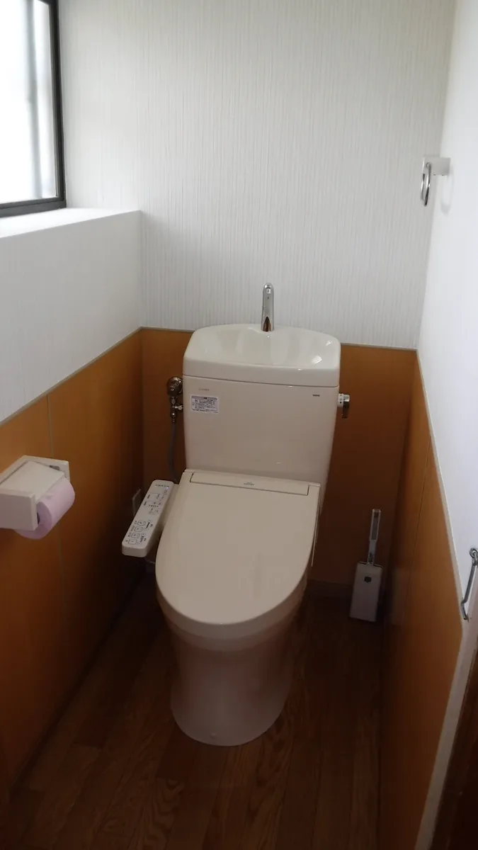 施工後のトイレ。新しい便器と温水洗浄便座、腰壁に張ったパネル