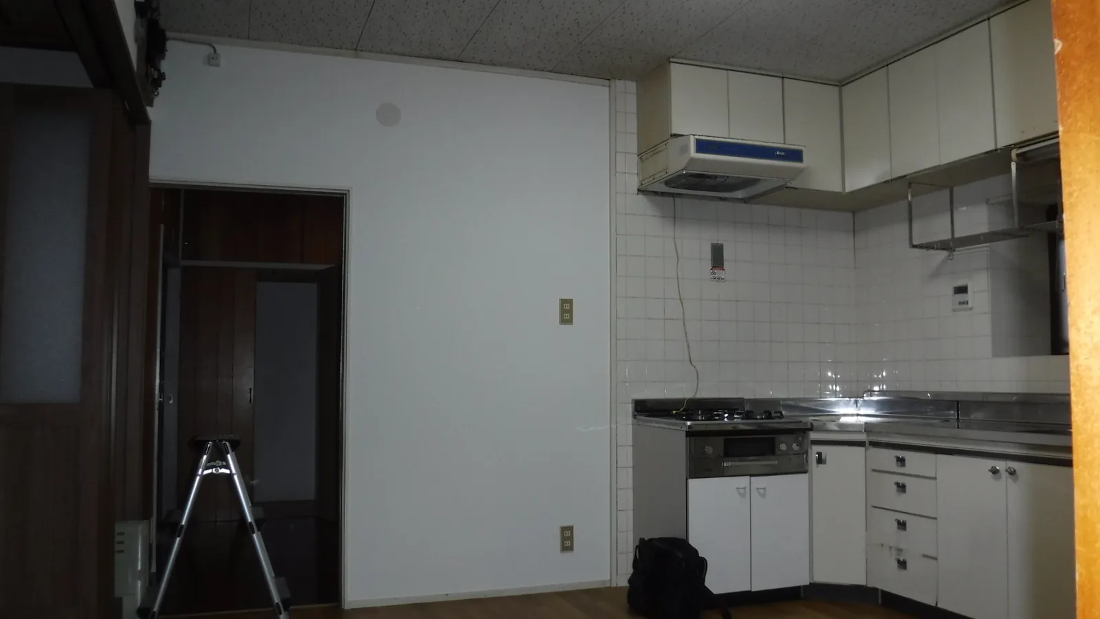 施工前のキッチンと、その横の壁。白いタイル壁と換気扇