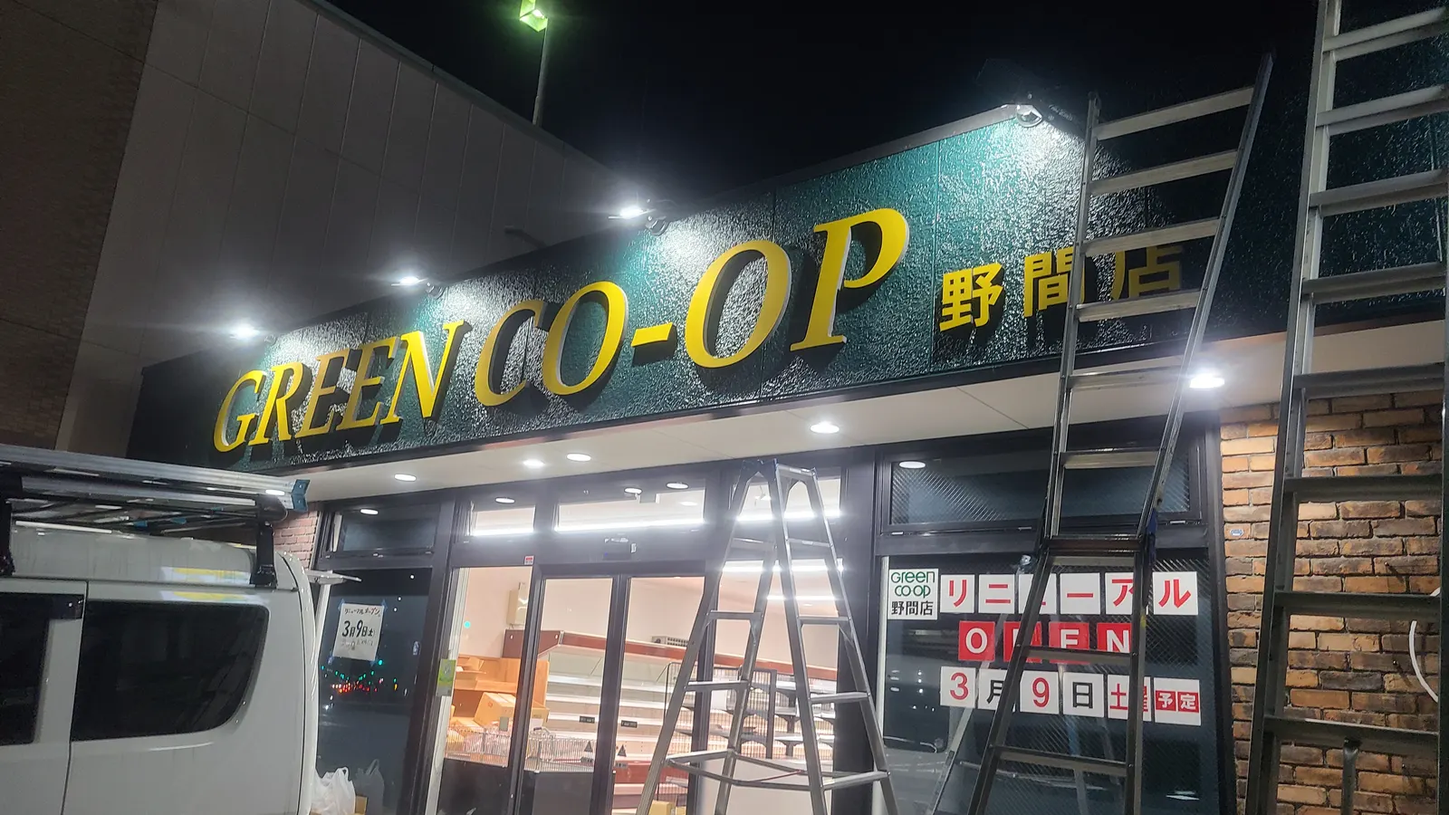 夜の店舗の外観。新しい看板が点灯している